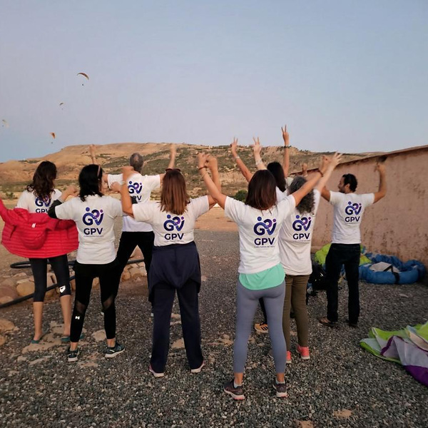 Équipe en t-shirts GPV, bras levés, sur un site de décollage de parapente